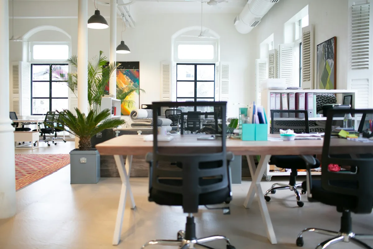 Unbesetzte Arbeitsplätze mit Schreibtischen und Bürostühlen in einem hellen Büro
